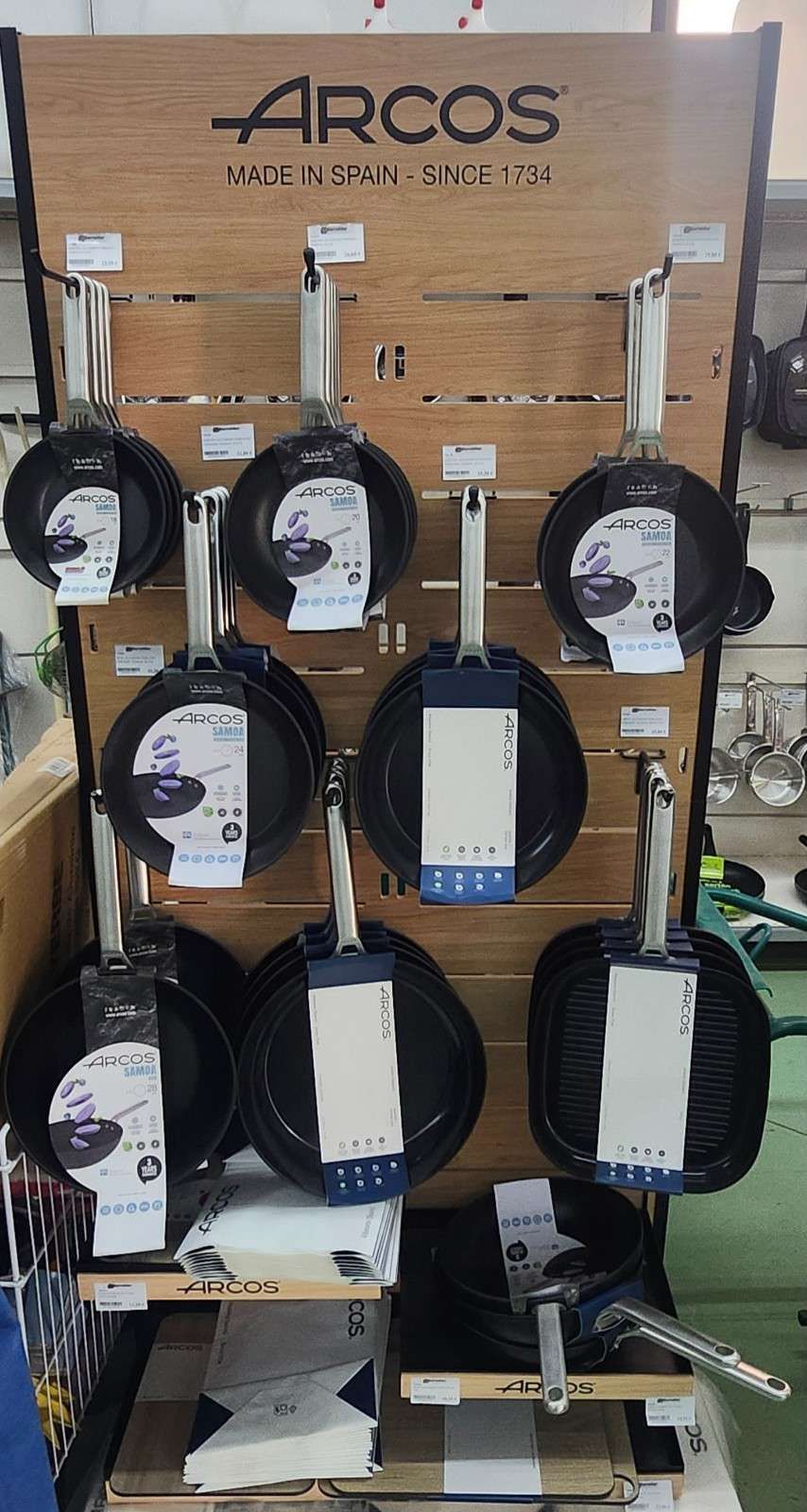 Filas de carretes de cable en blanco y negro montados sobre un panel de exhibición de madera en un entorno de almacén.