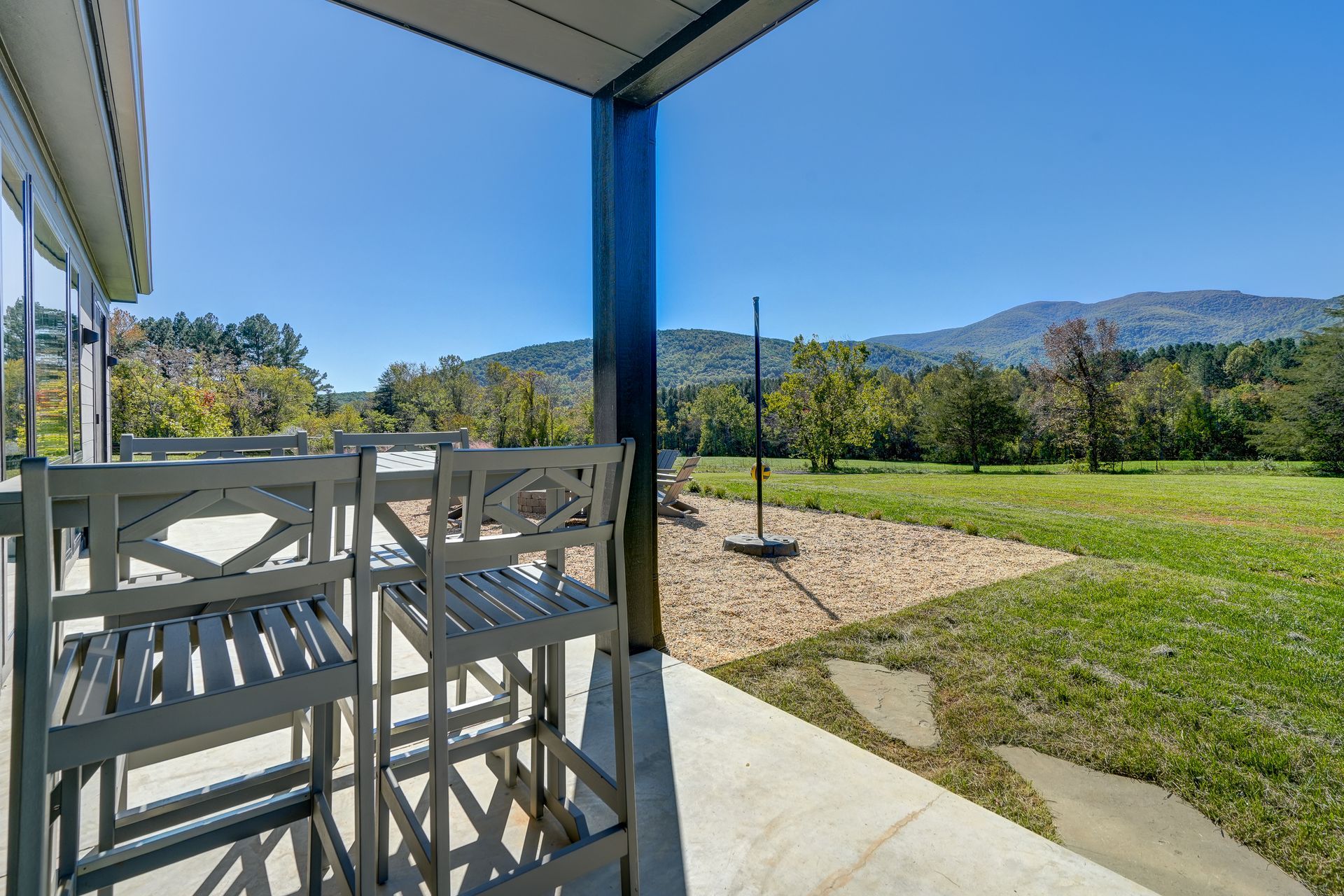 A patio with a view of a field and mountains.