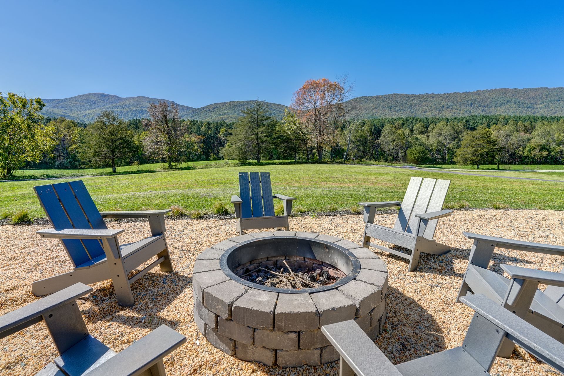 A fire pit surrounded by chairs on a patio with mountains in the background.