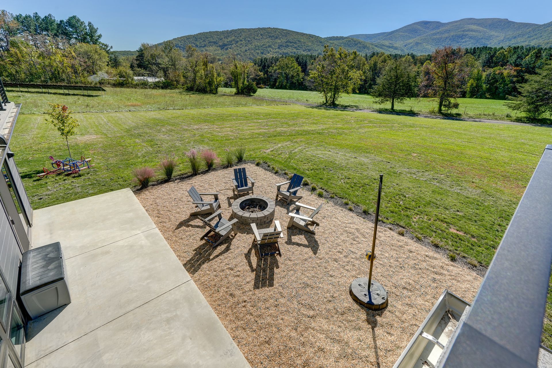 There is a fire pit and tether ball on a gravel patio.