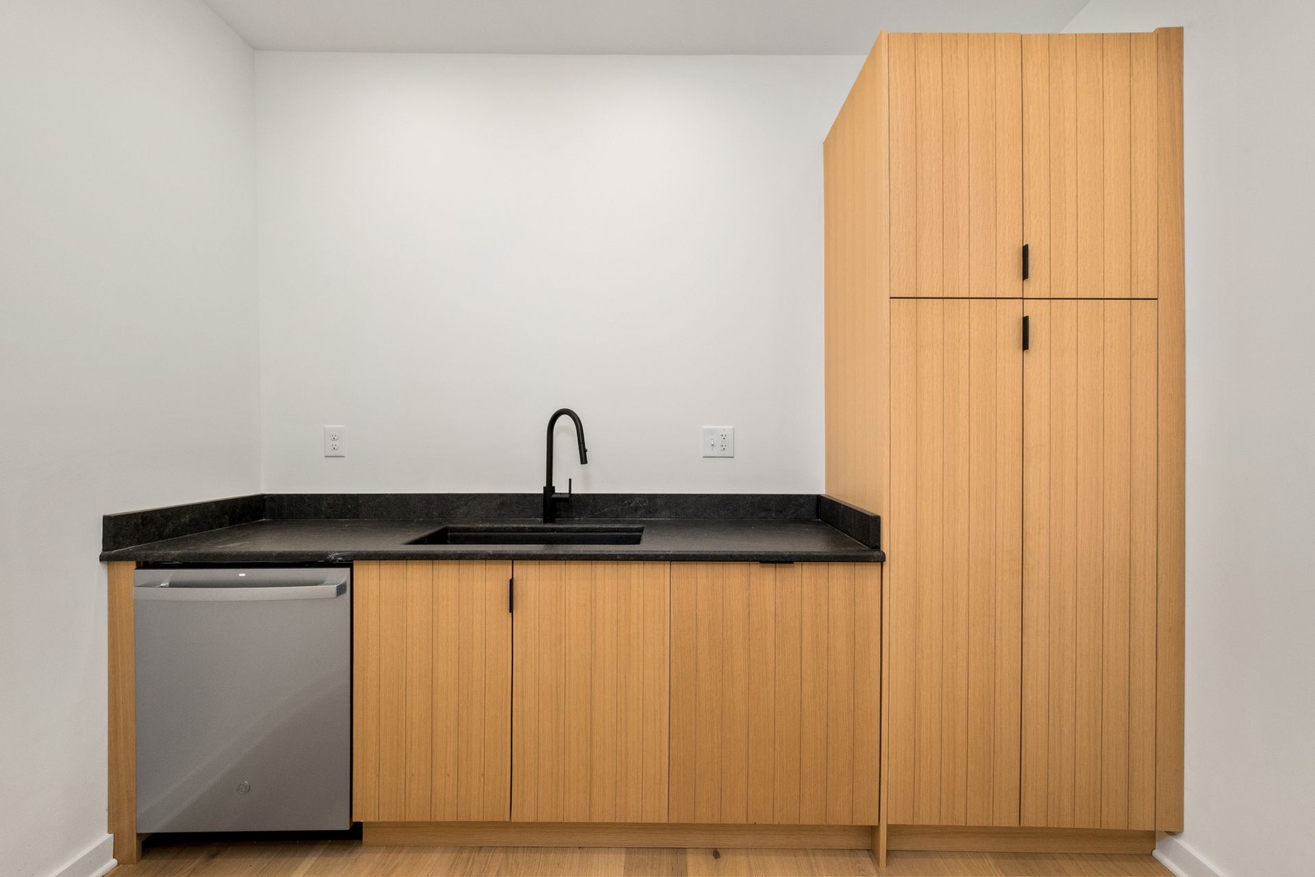 A kitchen with wooden cabinets , a sink , and a dishwasher.