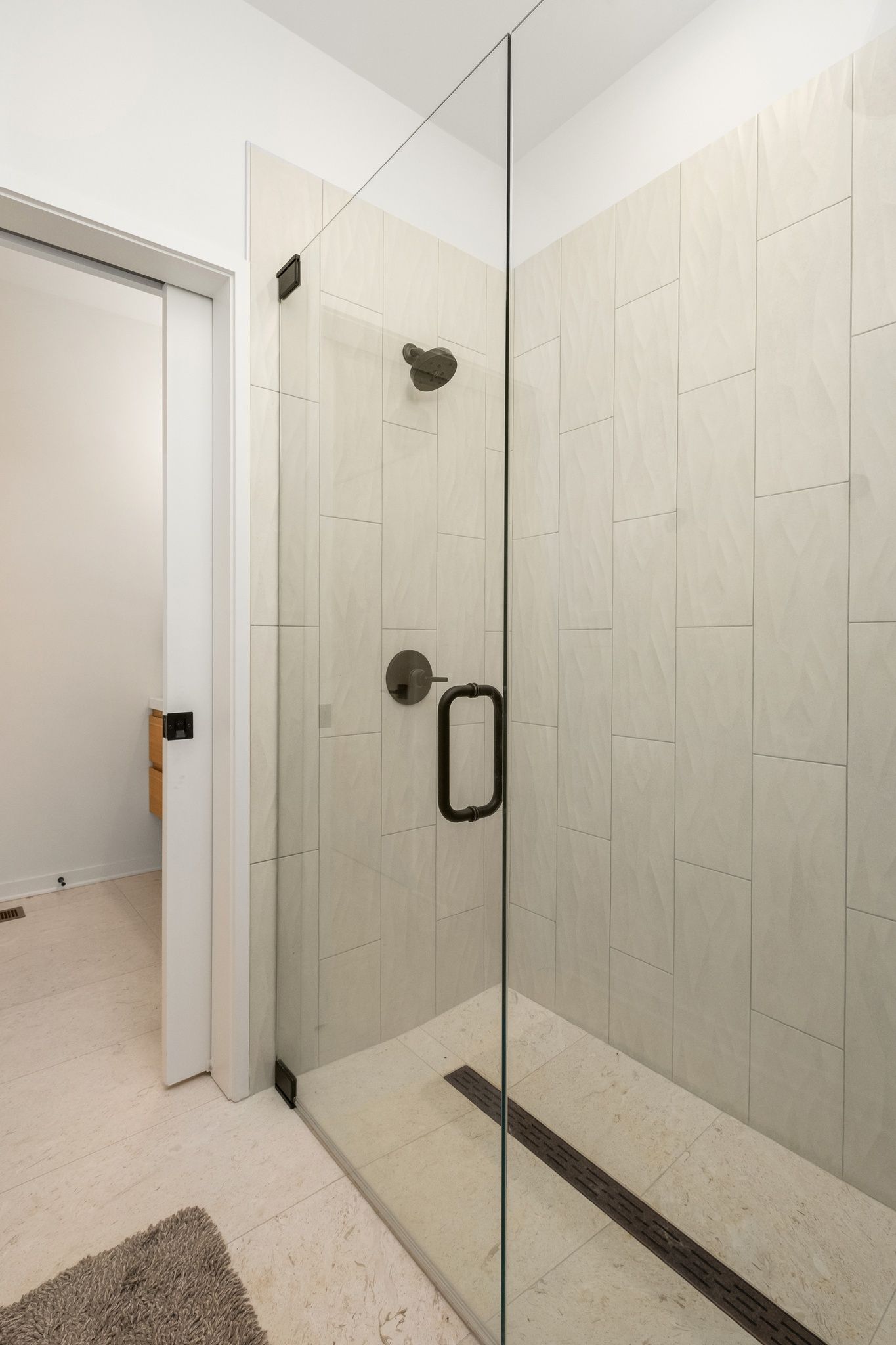 A bathroom with a walk in shower with a glass door.