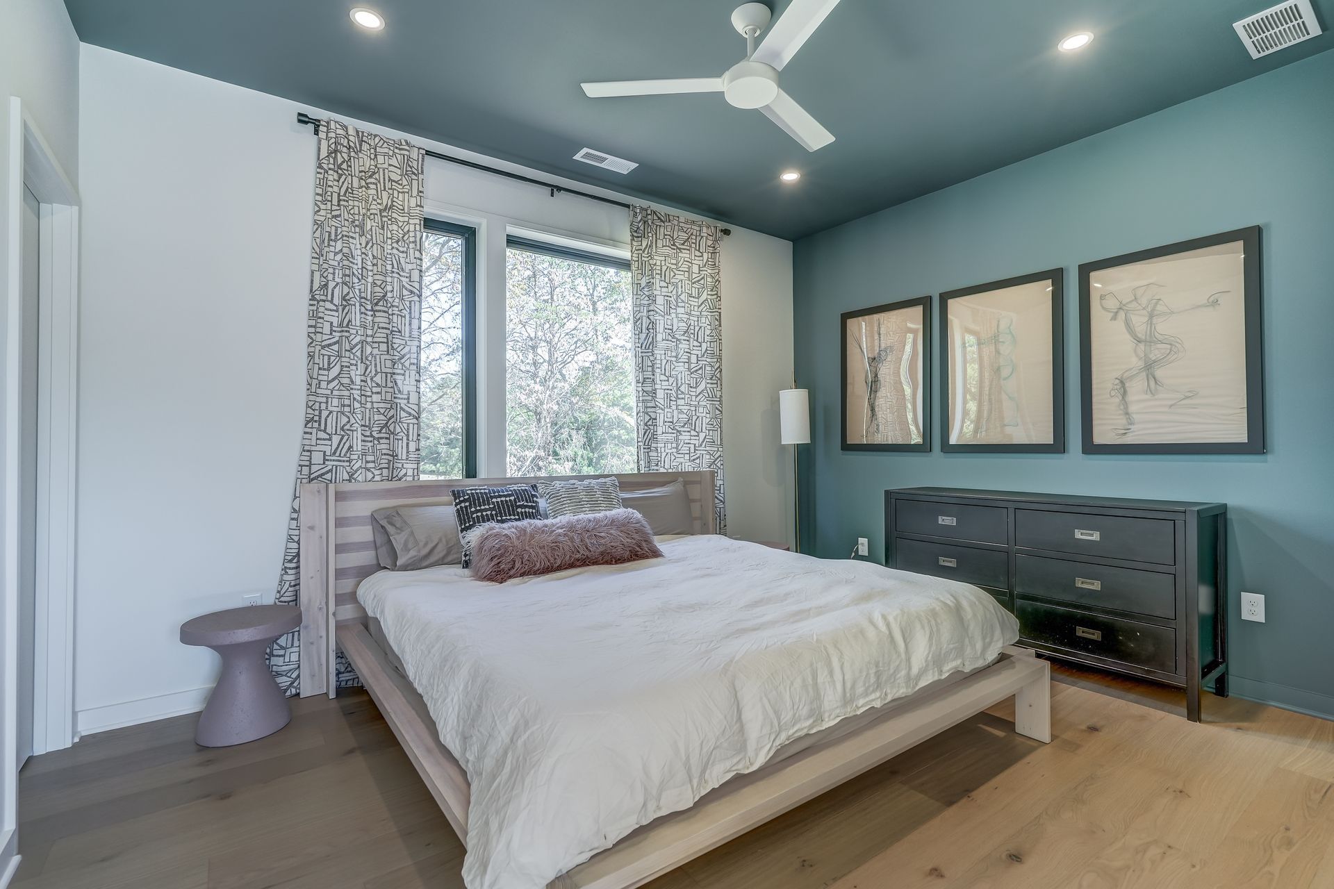 A bedroom with a bed , dresser , and ceiling fan.