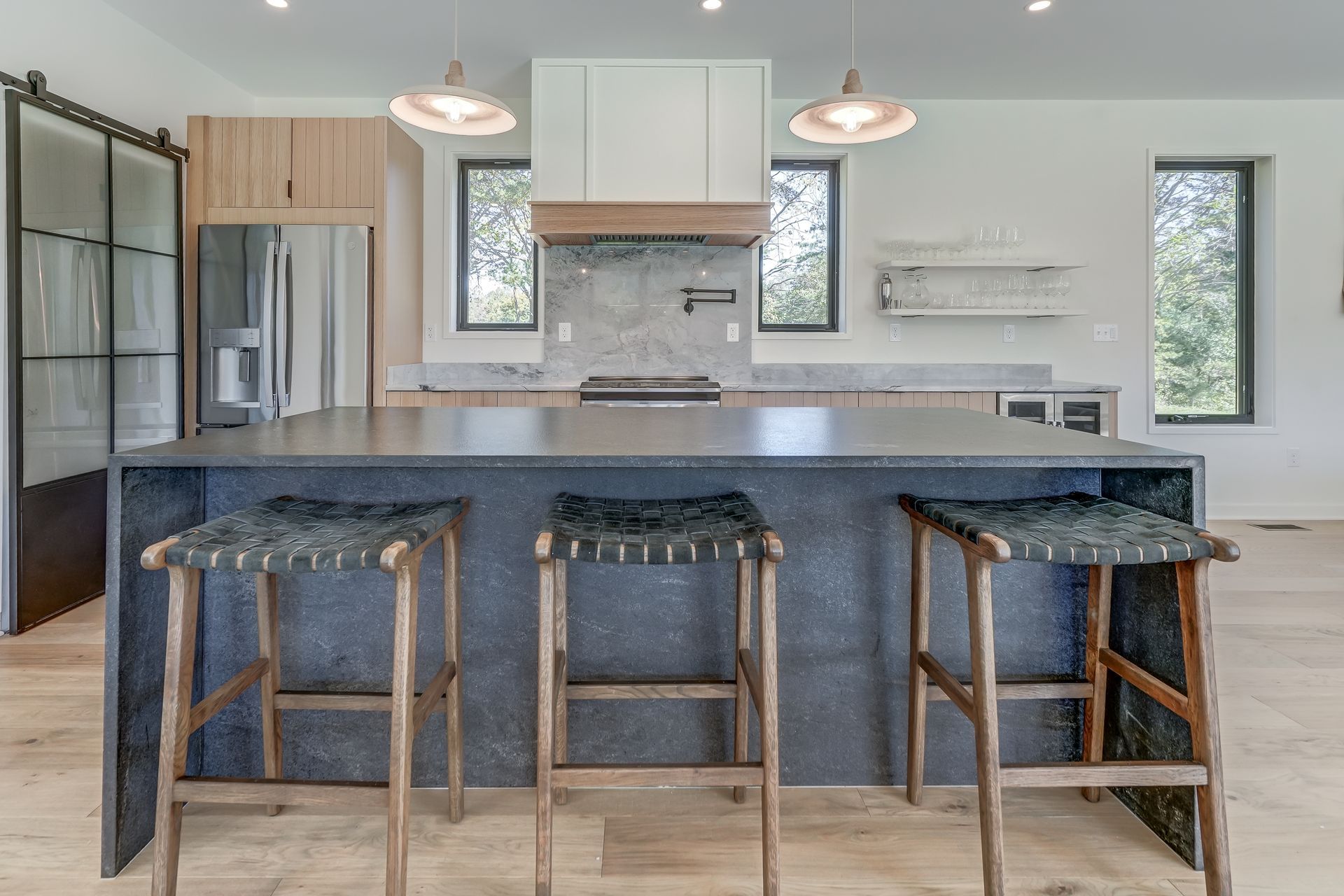 A kitchen with a large island and three bar stools.