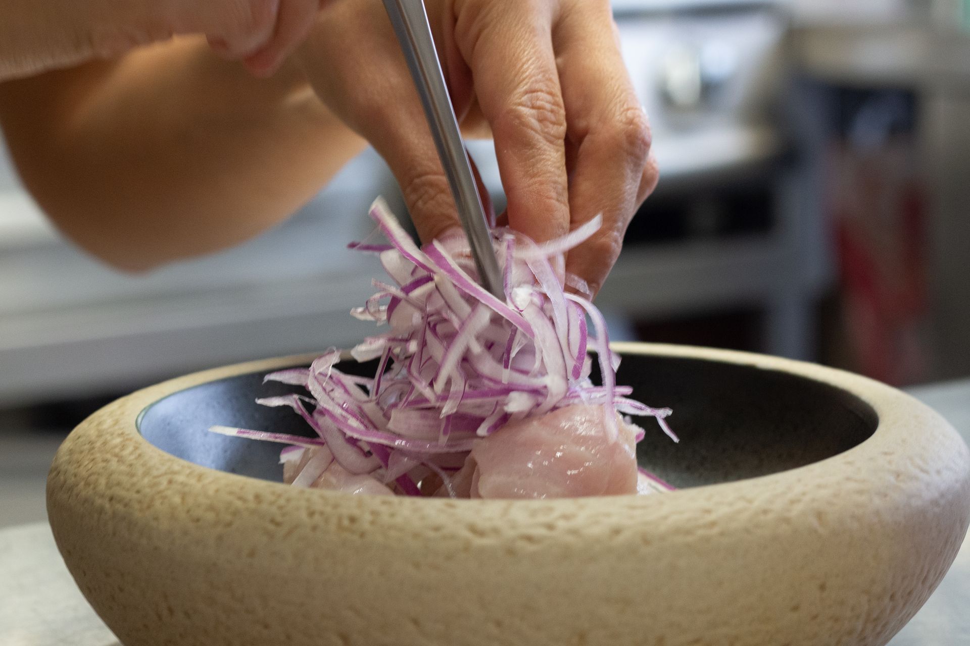 Una persona está poniendo cebollas en un recipiente con comida.