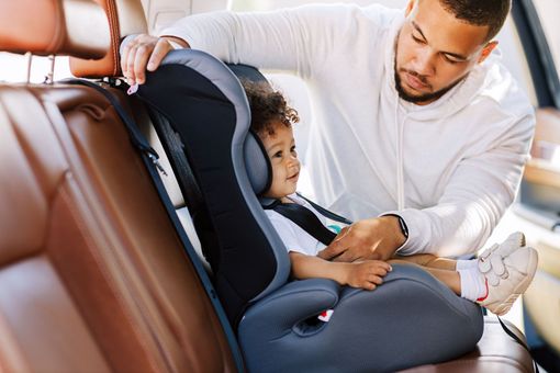 Un papa qui met son enfant dans le siège auto de la voiture