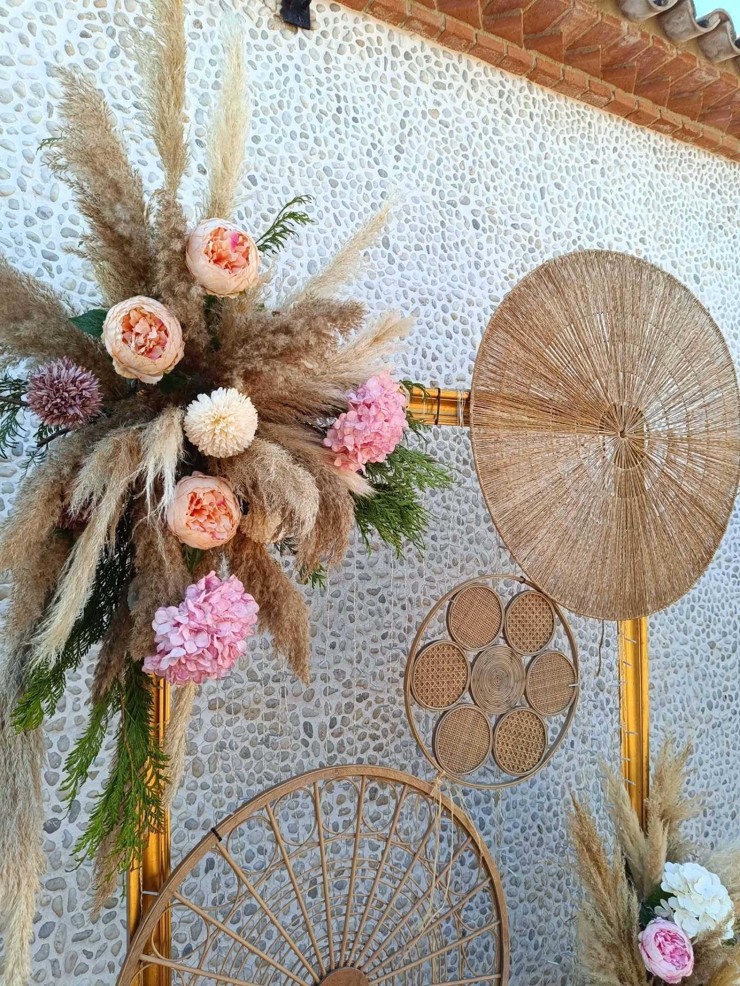 Arco floral con flores rosas y decoraciones circulares tejidas.