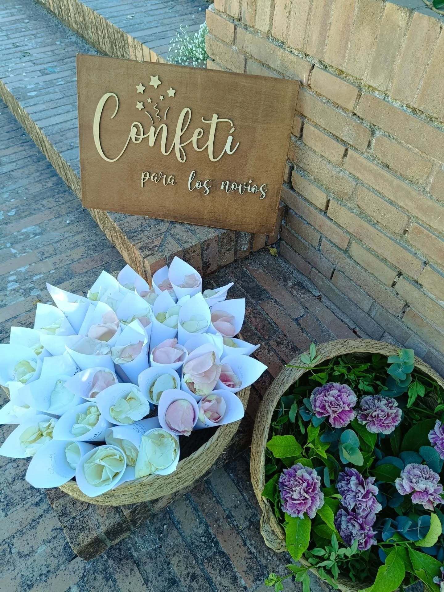 Canasta de conos de confeti y flores cerca de un letrero de madera que dice