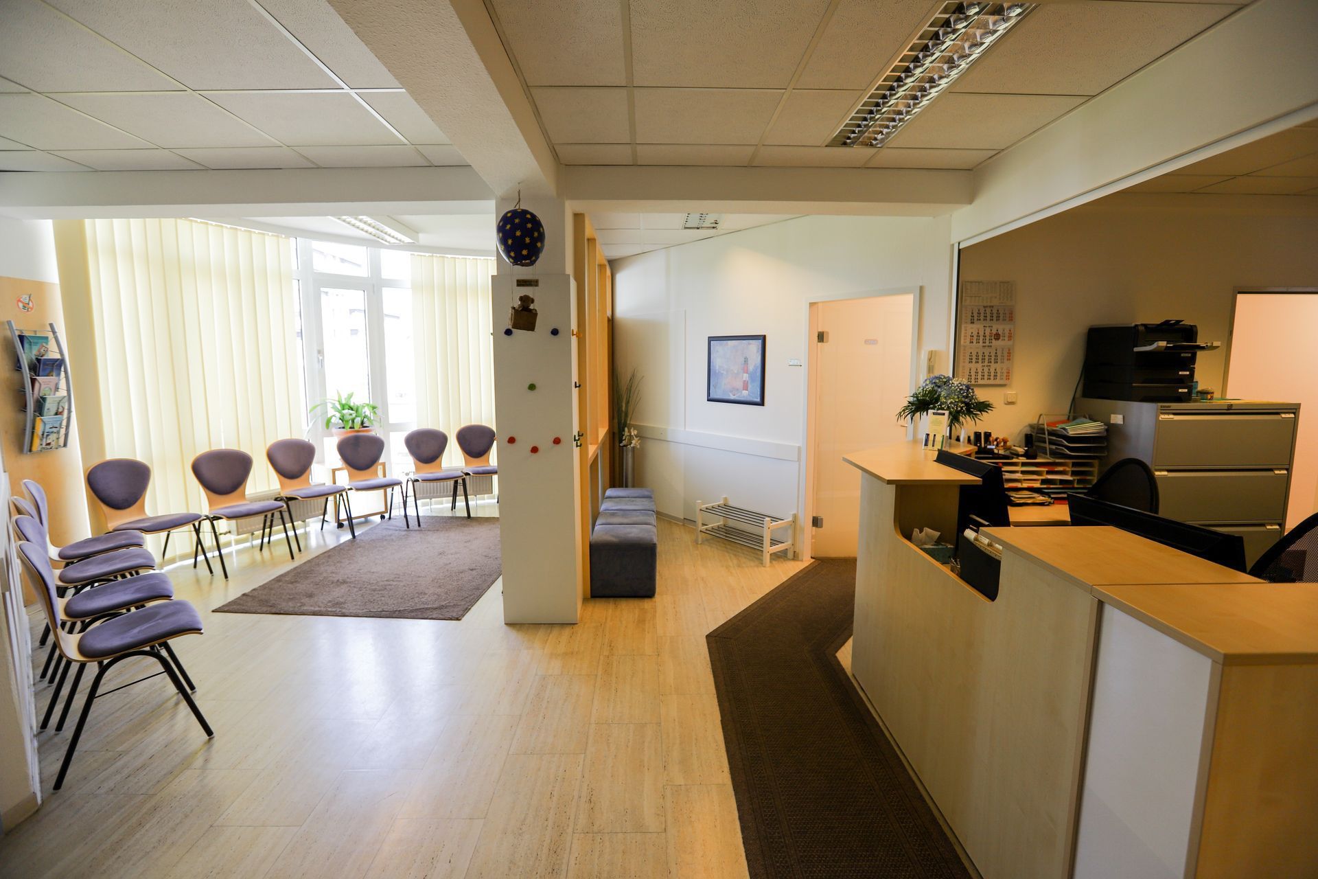 Empfangsbereich mit Schreibtisch, Stühlen und Wartebereich.