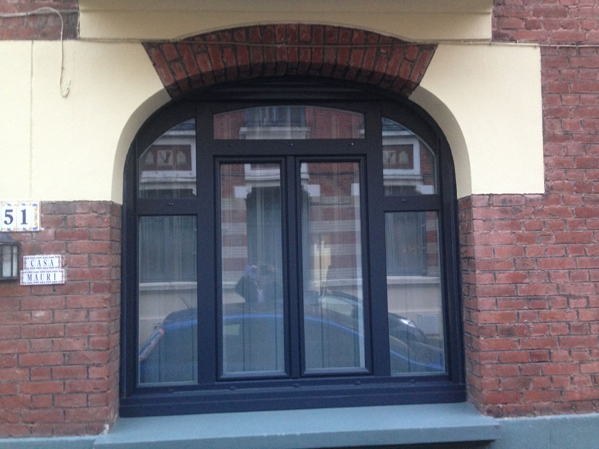 Fenêtre cintrée sombre dans un bâtiment en briques.