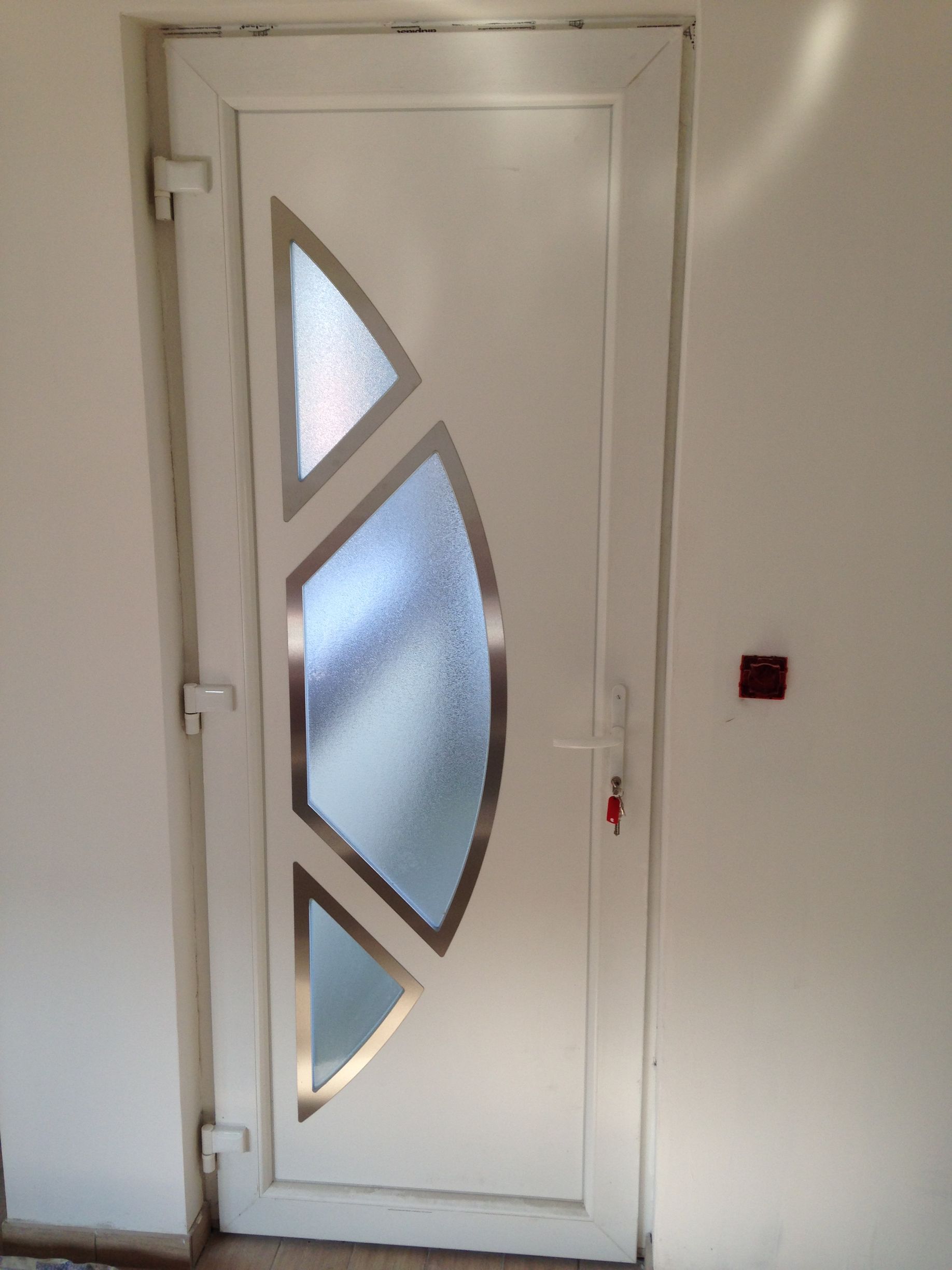 Porte blanche avec panneaux en verre dépoli et contours en acier inoxydable.