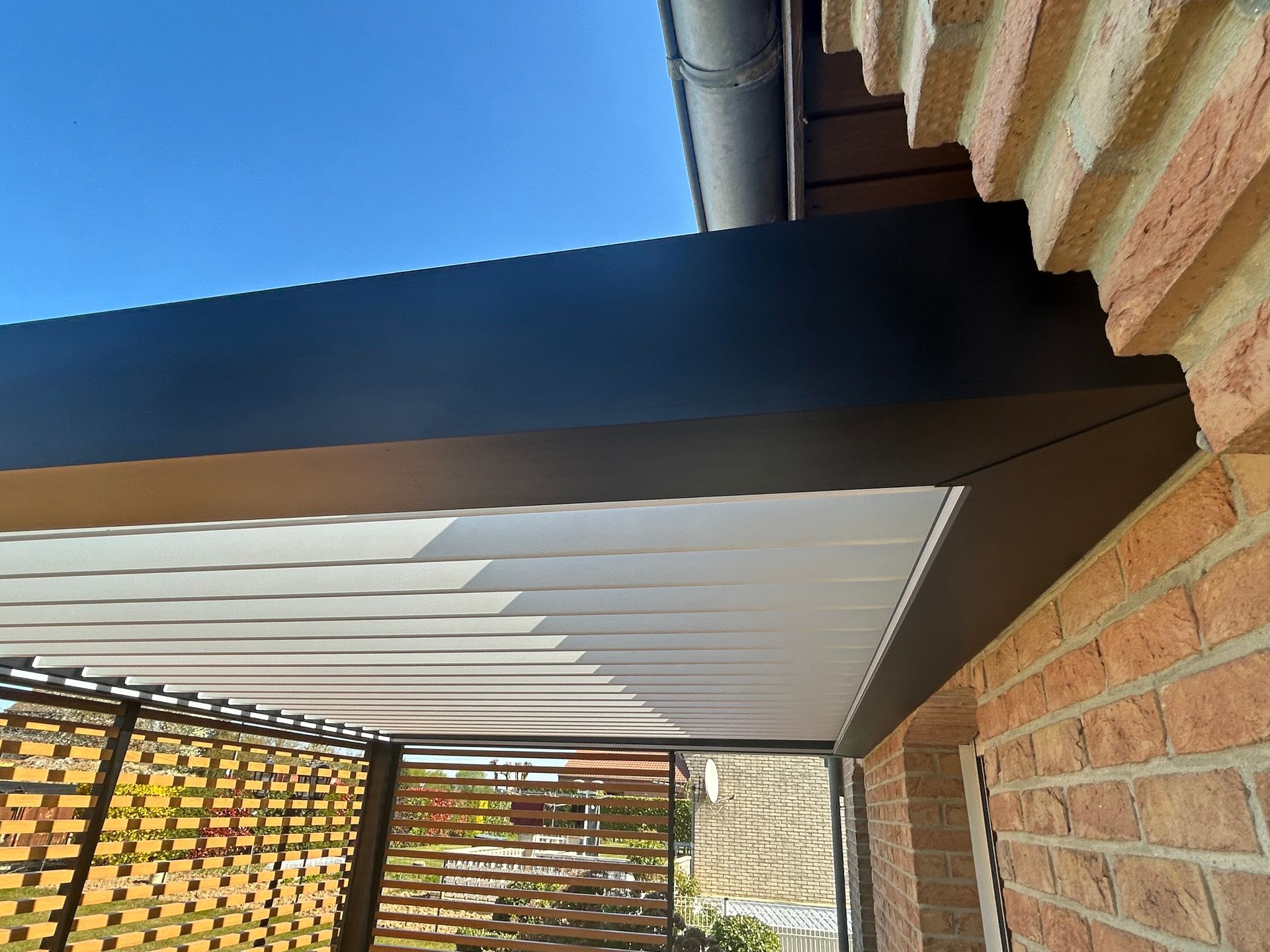 Vue ciblée sur le toit d'une pergolas avec lames orientables.