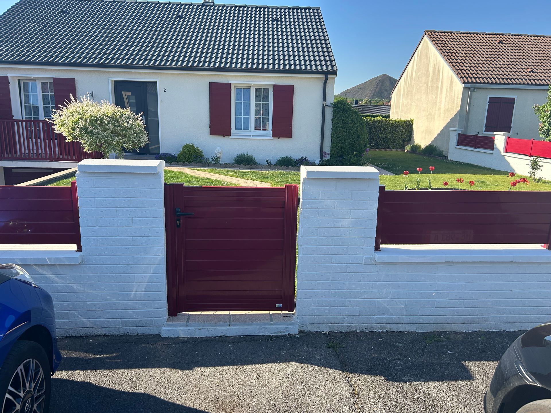 Maison blanche avec volets, clôture et portail bordeaux.