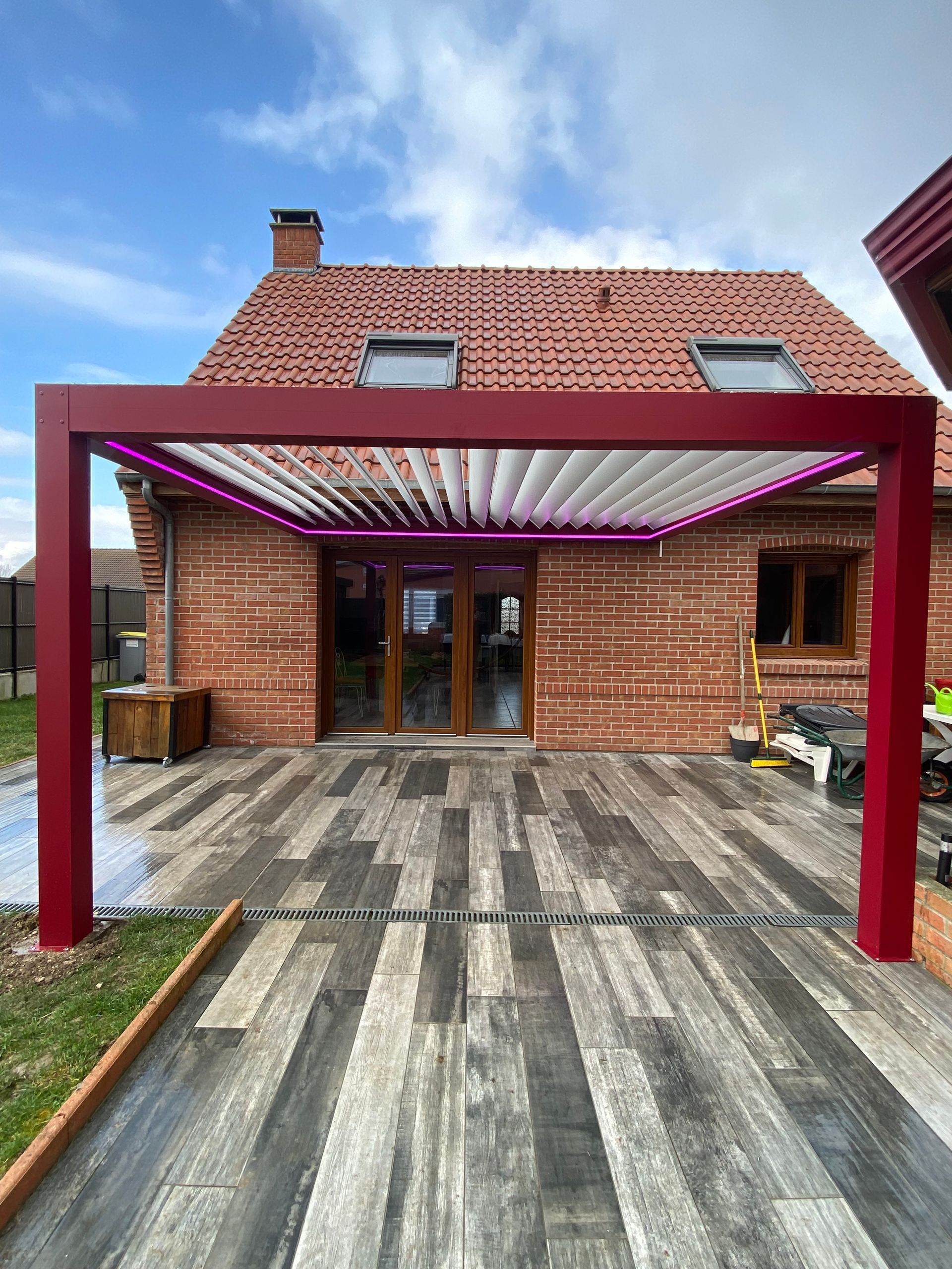 Pergola rouge avec néons roses au-dessus d'une terrasse.