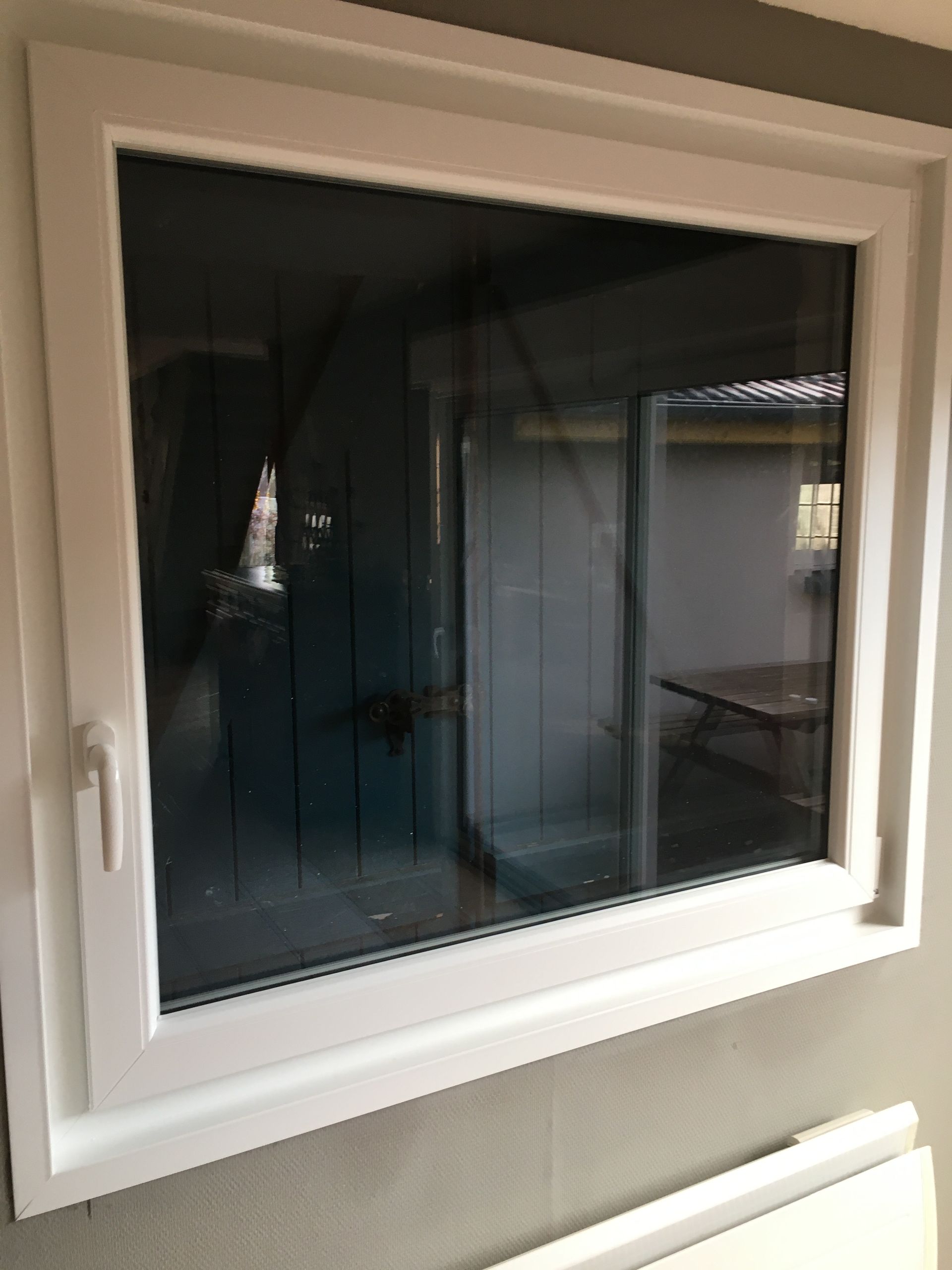 Fenêtre à cadre blanc dans un mur, reflétant une pièce avec une table.