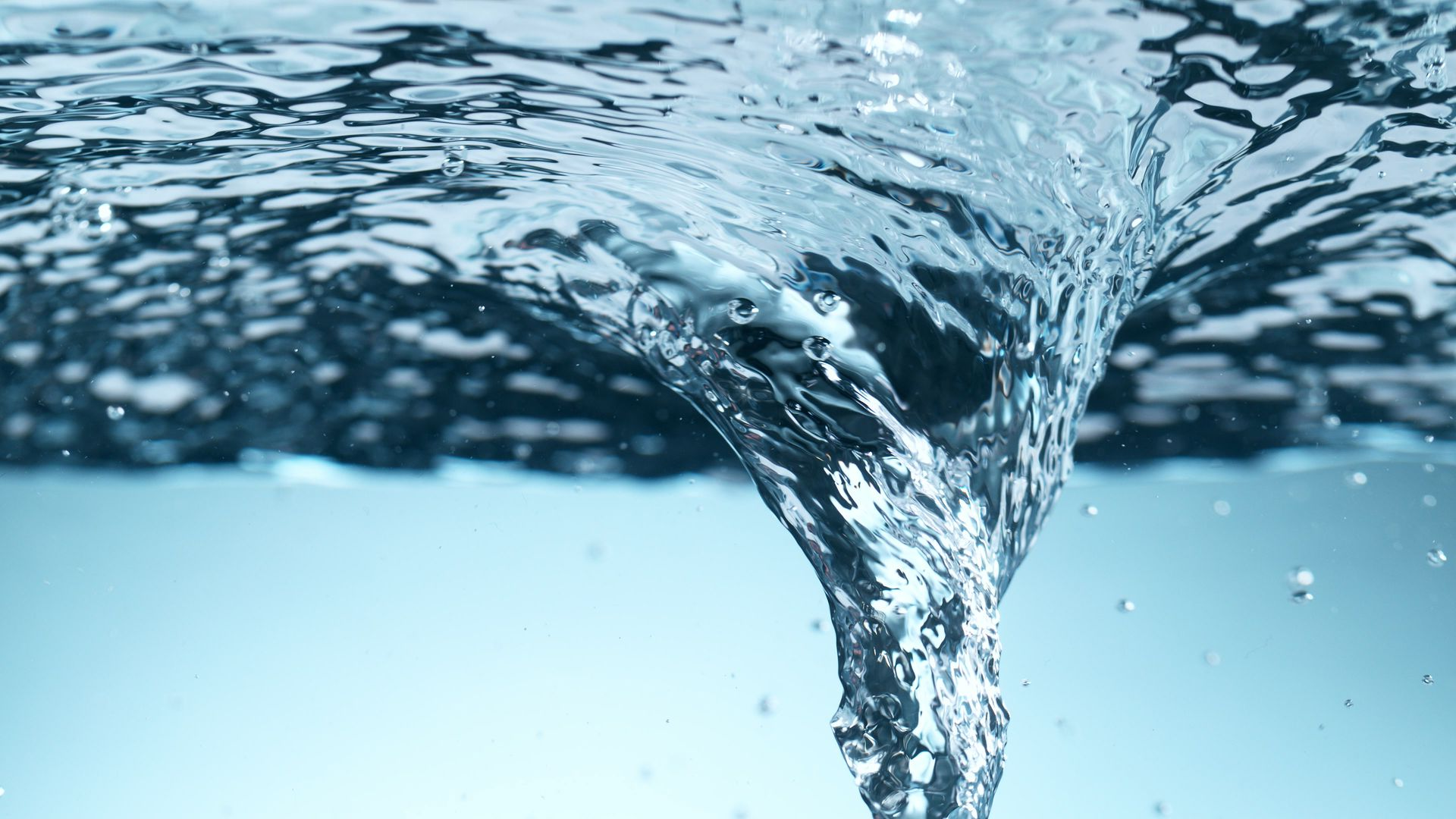 Tourbillon d'eau formant un vortex, avec de l'eau bleue claire et des bulles visibles.