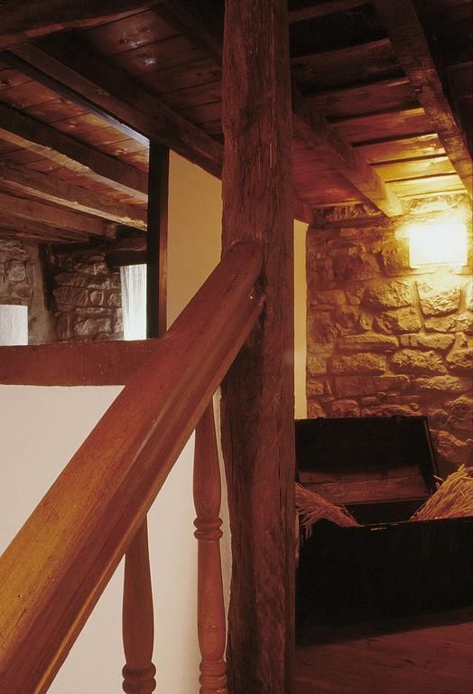 Escalera de madera con viga de madera texturizada que conduce a una zona con paredes de piedra.