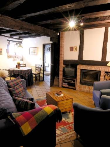 Acogedora sala de estar con chimenea, vigas a la vista y sofás azules; alfombra colorida.