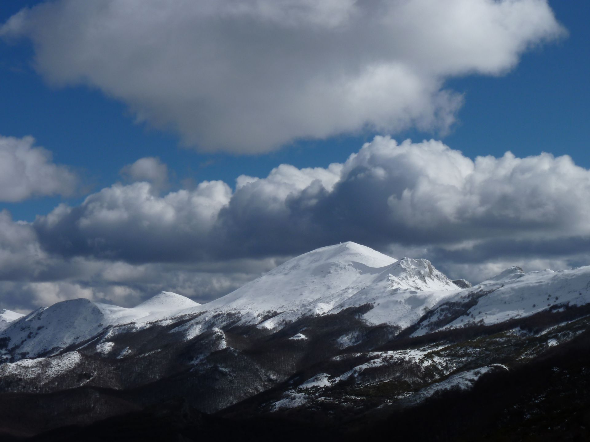 Montañas cubiertas de nieve bajo un cielo azul parcialmente nublado.