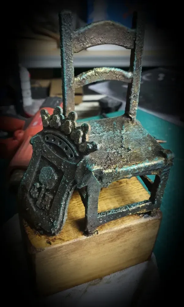 Una pequeña silla con una corona sobre ella está colocada sobre un bloque de madera.