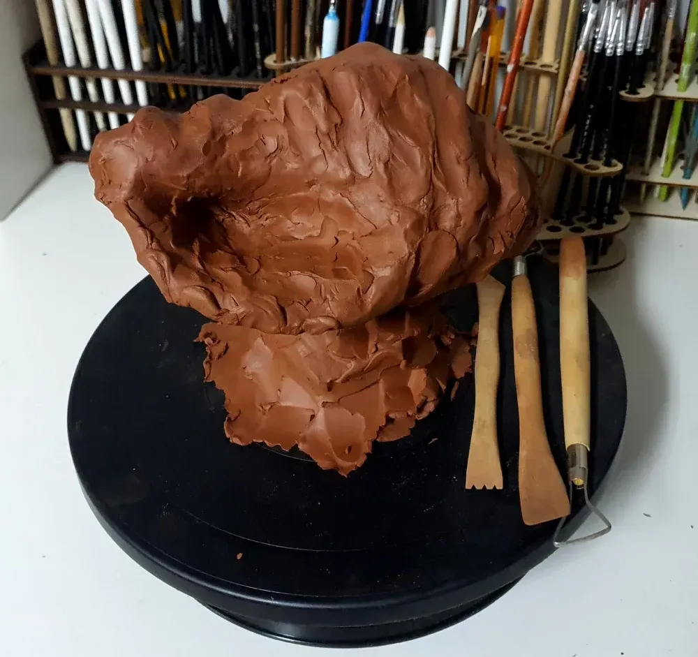 Un montón de arcilla marrón reposa sobre un plato negro.