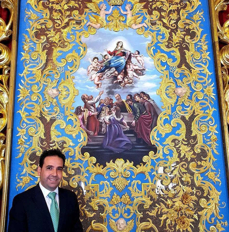 Un hombre con traje y corbata se encuentra frente a un cuadro grande.