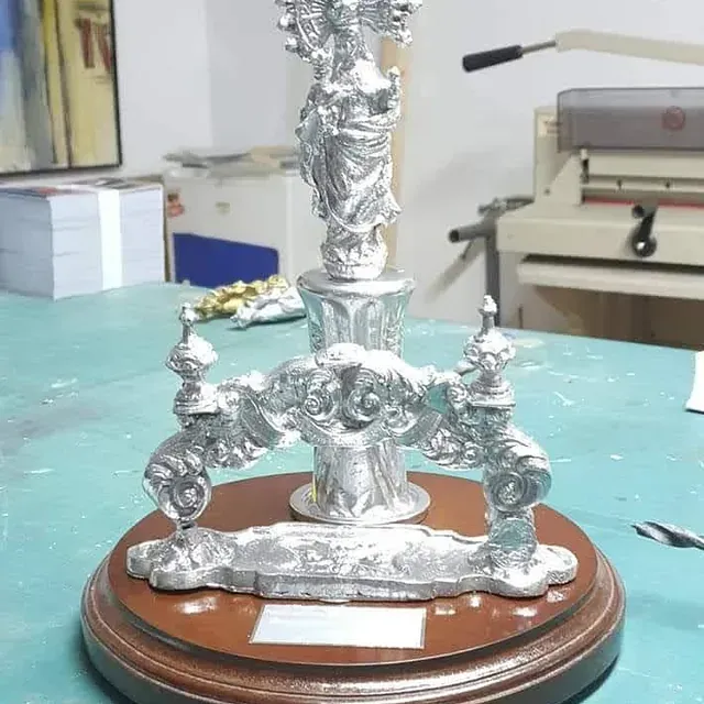 Una estatua de plata está sentada sobre una base de madera.