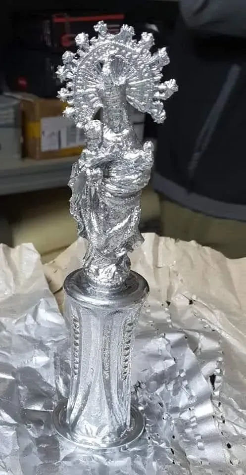 Una estatua de plata de una mujer está sentada encima de un trozo de papel.