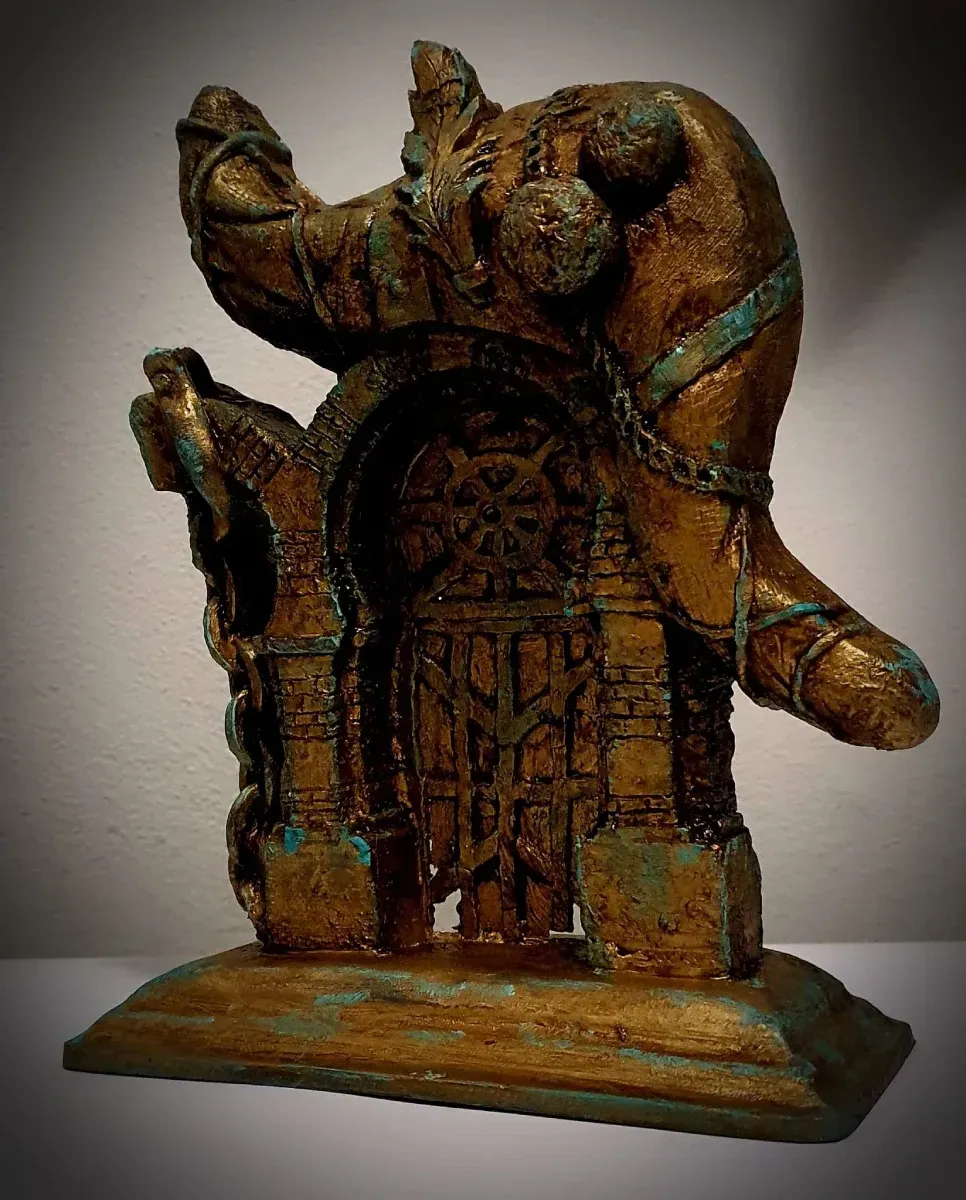 Una estatua de un hombre con cadenas alrededor de su cuello está sentada sobre una mesa.