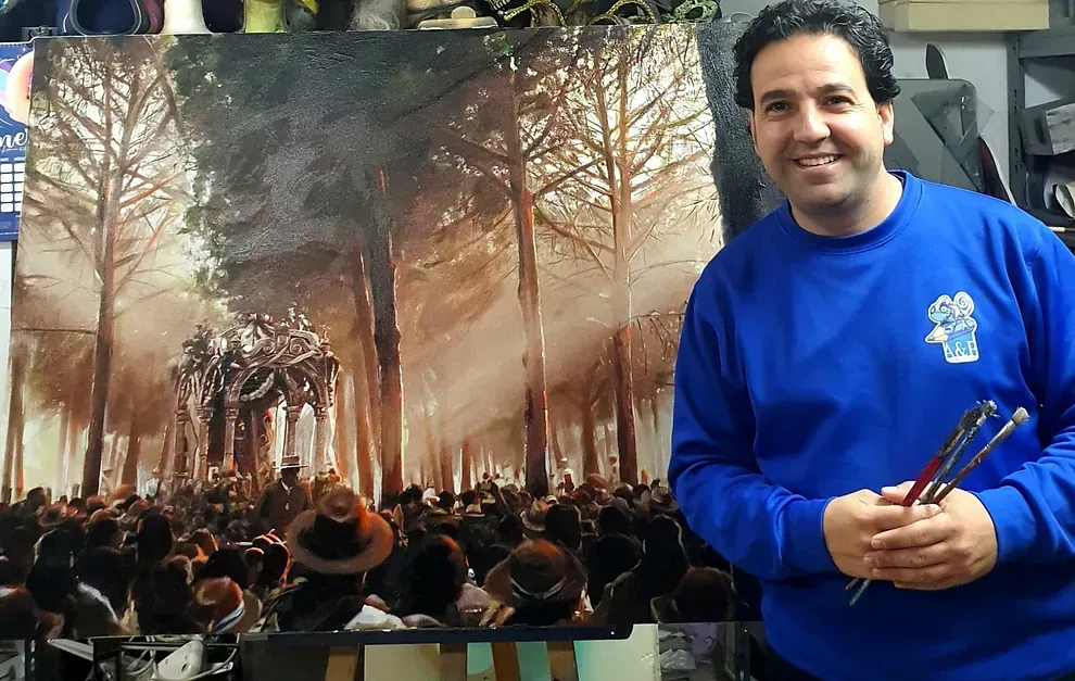 Un hombre con una camisa azul está parado frente a un cuadro.