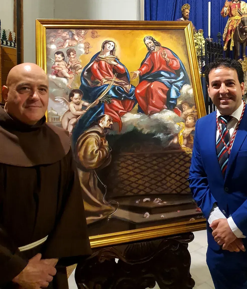 Dos hombres de pie delante de un cuadro de Jesús y María.