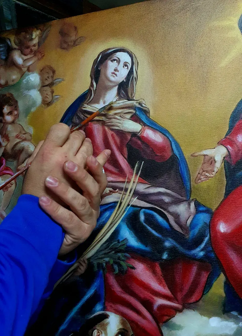 Una pareja tomada de la mano delante de un cuadro de Jesús y María.