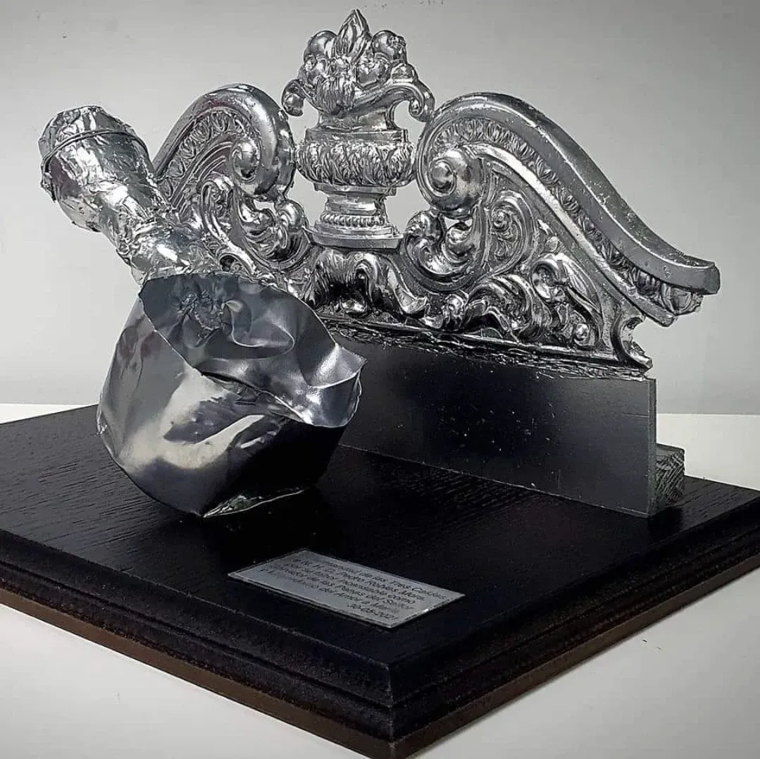 Una escultura de plata está sentada sobre una base negra.