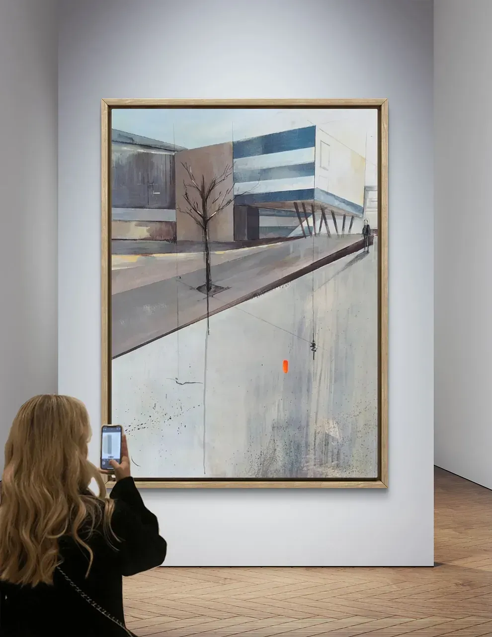 Una mujer está tomando una fotografía de un cuadro en un museo.