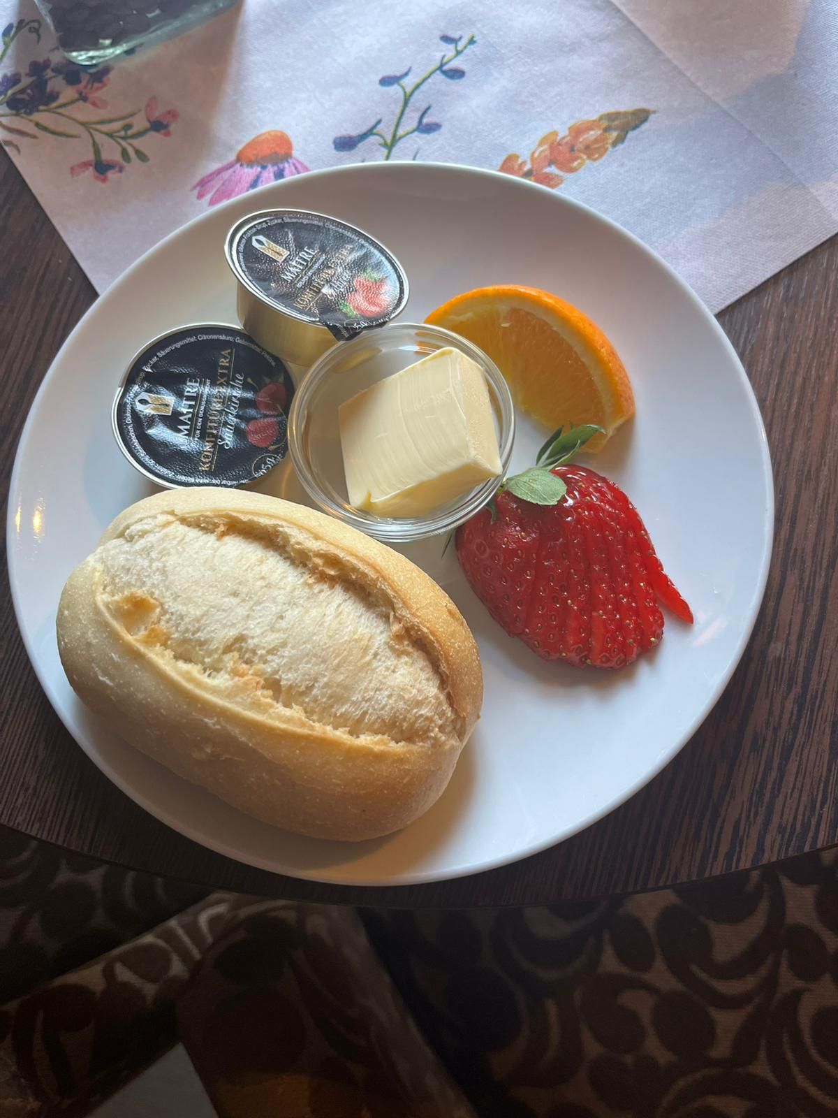 Ein weißer Teller mit Brotbutter, Erdbeeren und Orangenscheiben