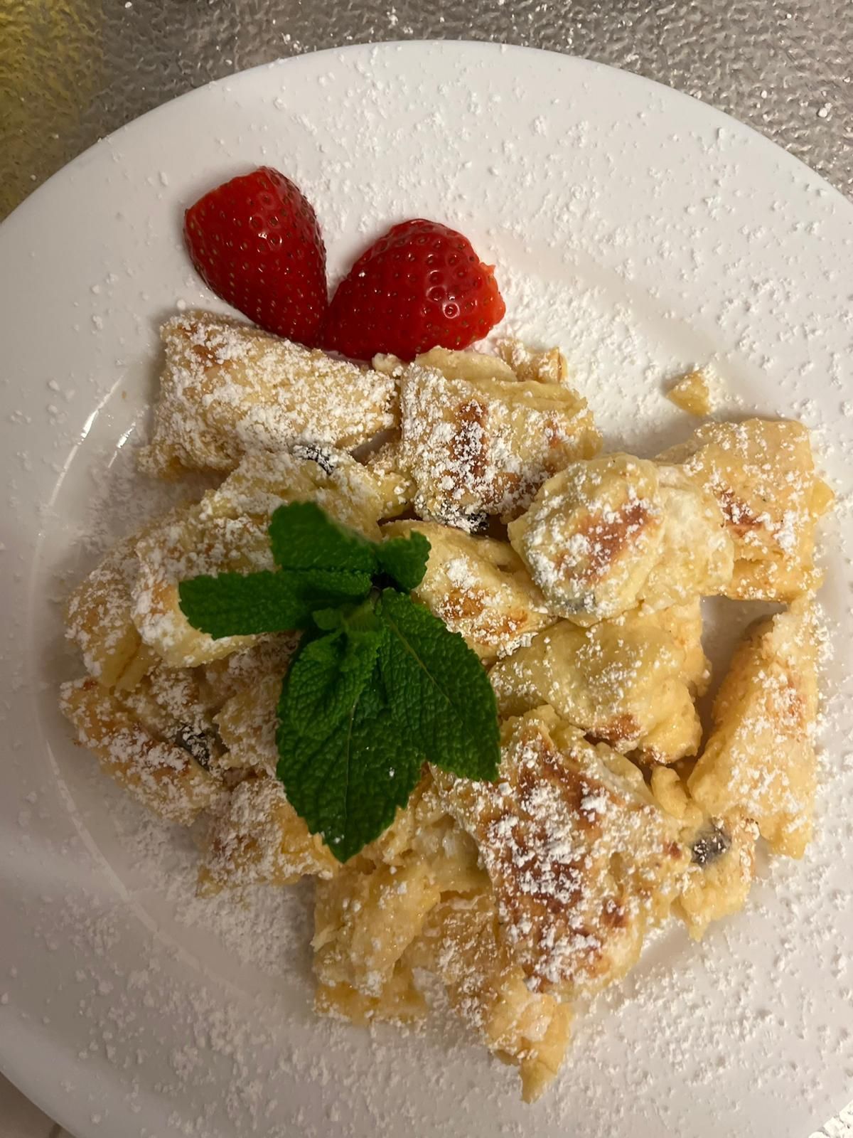 Ein Teller mit Essen, bestreut mit Puderzucker und Erdbeeren.