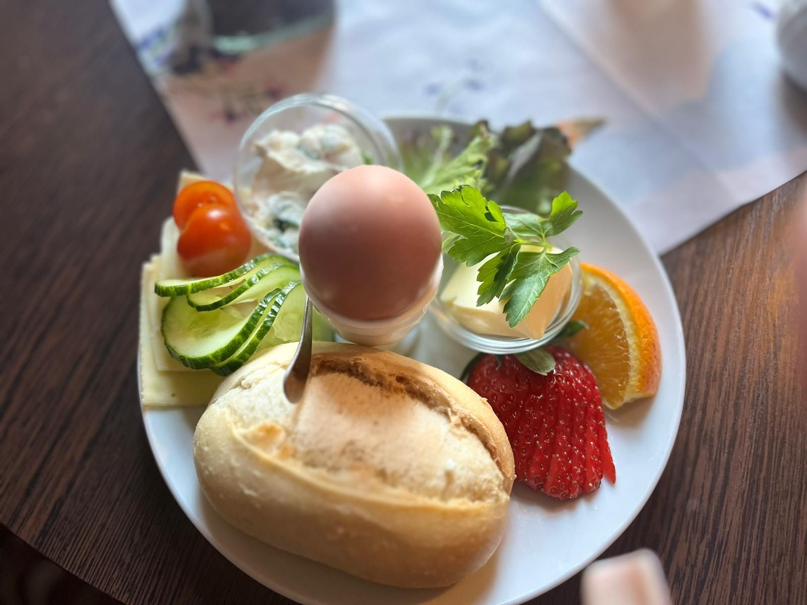 Ein Teller mit Eiern, Brot, Gemüse und Obst auf einem Tisch.