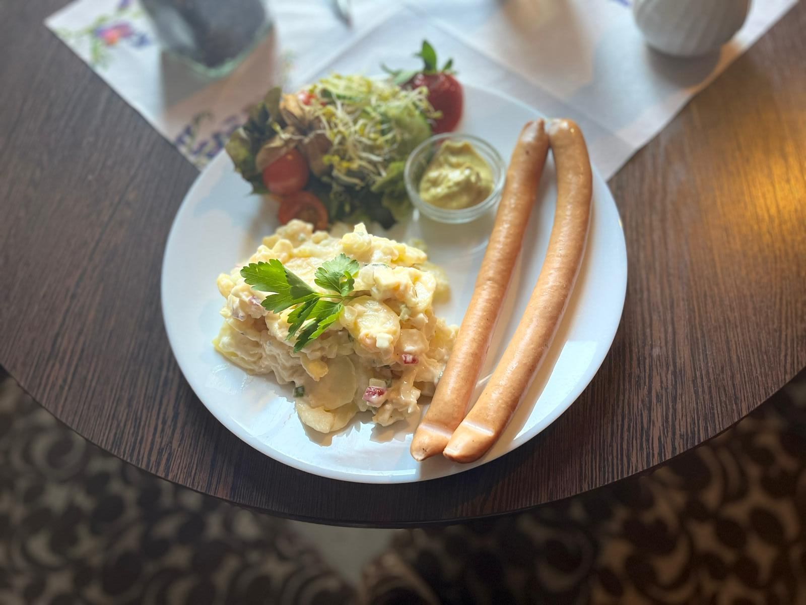 Ein Teller mit Rührei und Würstchen auf einem Tisch.