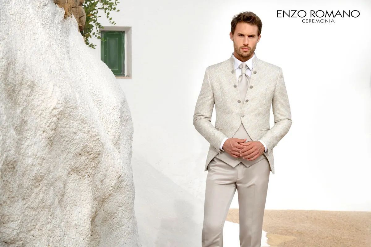 Un hombre con traje claro se encuentra frente a una pared blanca, debajo del logo de 