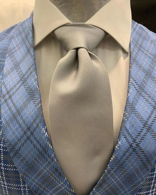 Primer plano de un traje a cuadros azul con corbata gris y camisa de cuello gris claro.