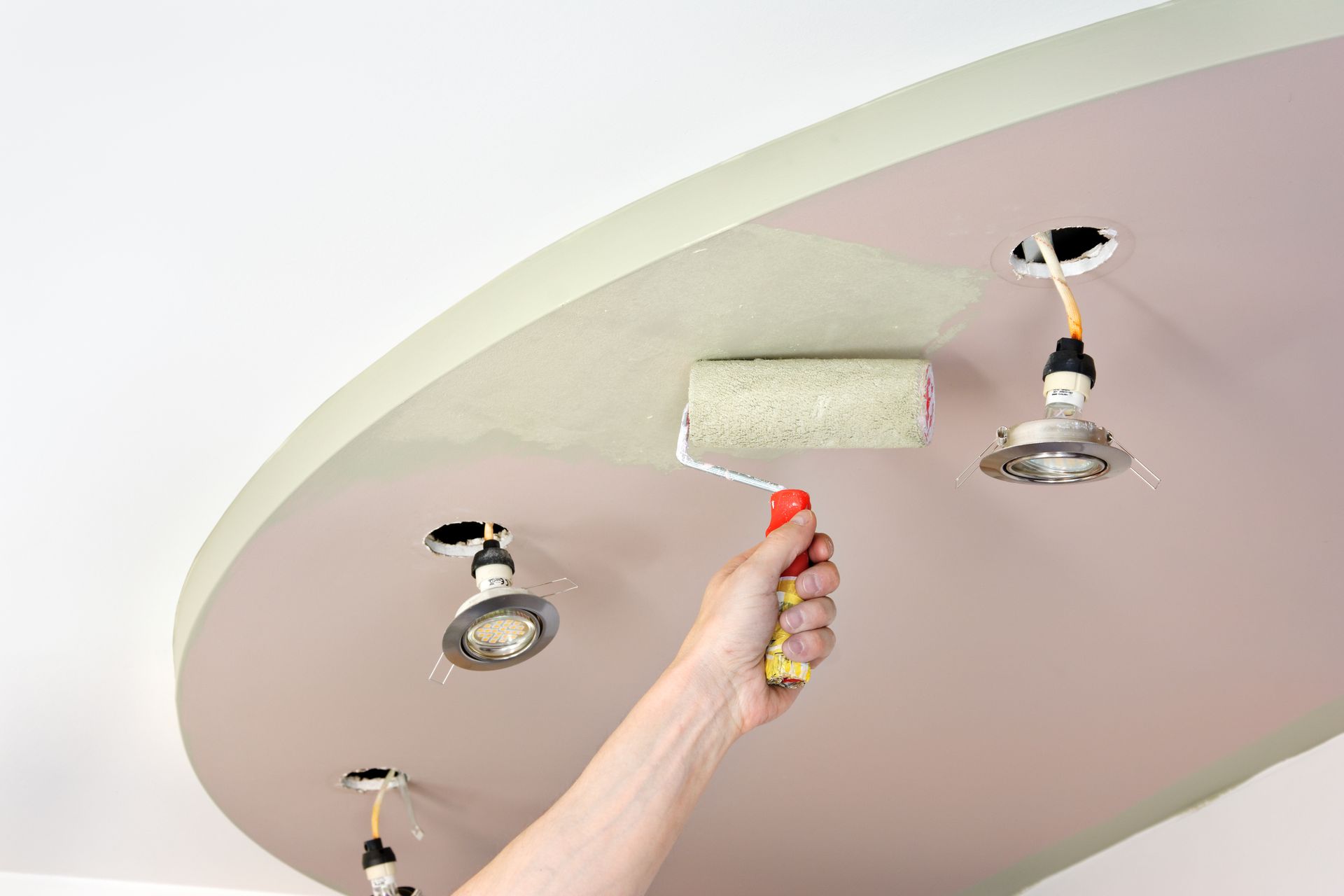 Homme peignant un faux plafond en médium avec des spots intégrés