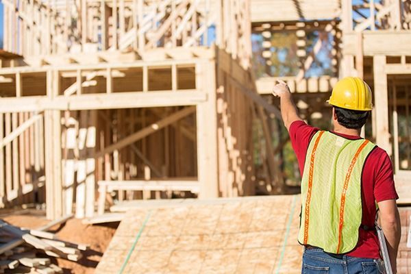 Un trabajador de la construcción está parado frente a un edificio en construcción.