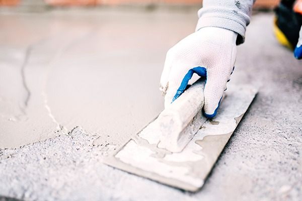 Una persona está usando una paleta para esparcir cemento sobre una superficie de concreto.