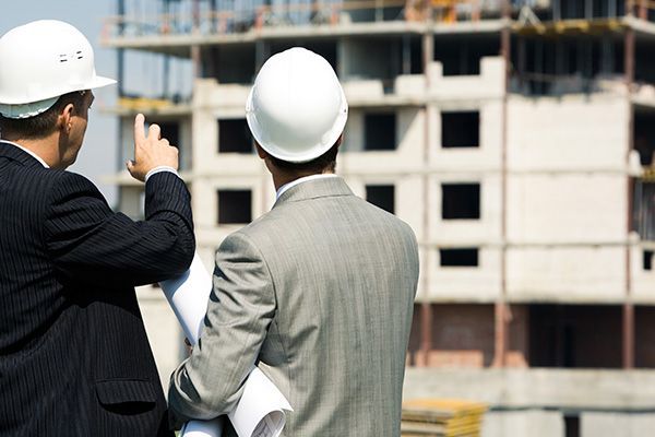 Dos hombres con cascos miran un edificio en construcción.