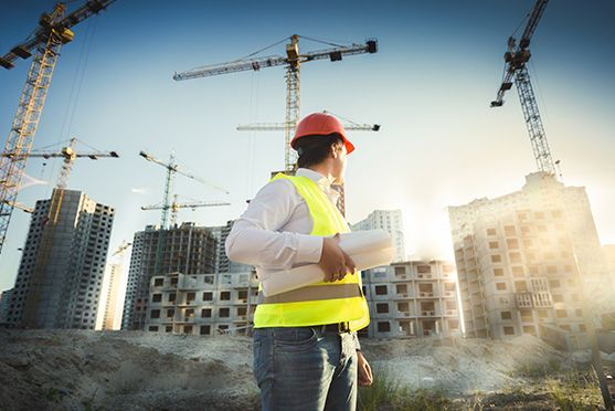 Un trabajador de la construcción está mirando un plano en un sitio de construcción.
