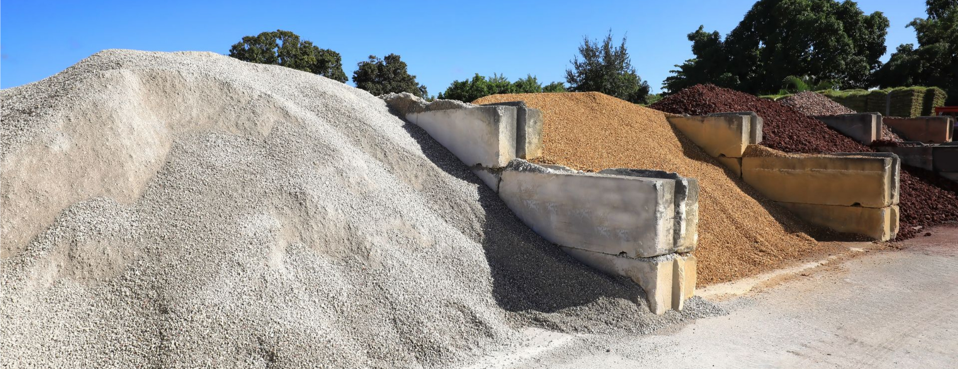 Des tas de gravier de couleurs variées, séparés par des murs de soutènement en béton, à l'extérieur.