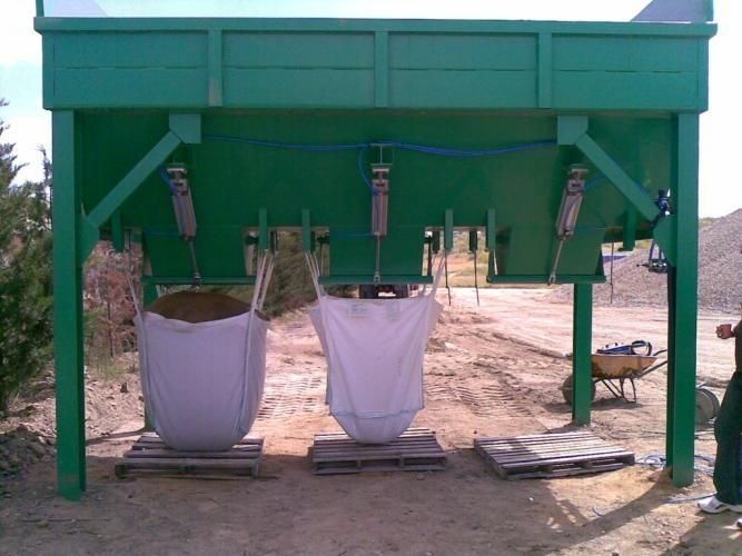 Tres bolsas de tierra están debajo de una estructura verde.