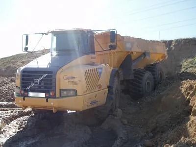 Un camión volquete amarillo circula por un camino de tierra.