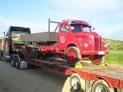 Un camión rojo está sentado encima de un remolque de plataforma.