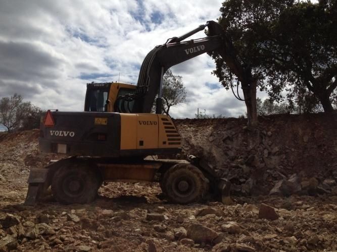 Una excavadora Volvo amarilla y negra está cavando en la tierra.